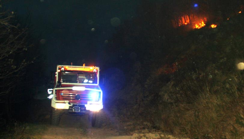 En la imagen se aprecian las cenizas en el aire, junto a la ladera incendiada en Vega de Pas