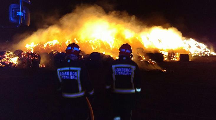 Bomberos del 112 trabajan en la extinción de un incendio en una pila de 1.500 pacas en Requejo